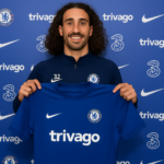 Digital sports news image showing Marc Cucurella, Chelsea defender, smiling while holding a Chelsea jersey after agreeing to a new contract.